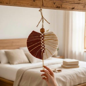 Peut inclure: Une décoration murale en macramé circulaire présentant un design divisé en deux, avec une moitié en corde couleur rouille profonde et l'autre moitié en corde crème. Une colonne vertébrale tressée centrale relie les deux parties.