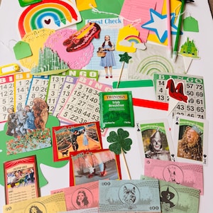 May include: A selection of Wizard of Oz themed items, such as bingo cards, playing cards, paper cutouts, and play money. The items feature characters, rainbows, and the Emerald City. A tea bag is also included.
