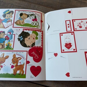 May include: An open book displaying vintage Valentine's Day cards. The cards feature illustrations of animals, including a dog, cat, and deer, along with hearts and the words "Valentine" and "Quick". The color palette includes red, blue, and brown.