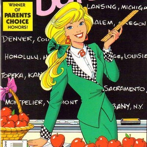 May include: Comic book cover featuring Barbie as a teacher. She wears a green blazer with a black and white checkered pattern, holding a ruler. A basket of apples and a pile of apples are in the foreground. The title "Barbie" is in pink.