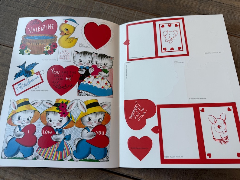 May include: Open book with vintage Valentine's Day illustrations. Features include a duck in a sailor hat, kittens, bunnies holding hearts, and heart-shaped cutouts. The text includes "Valentine" and "I love you."
