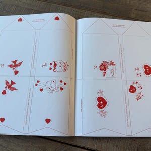 May include: Open book with pages featuring red illustrations on a white background. Designs include birds, cats, teddy bears, roses, and hearts. The text "I + U" is visible on some of the hearts. The pages are divided into sections with dotted lines.