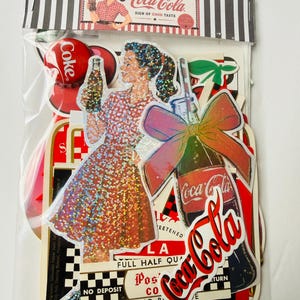 May include: A collection of Coca-Cola themed stickers in a clear plastic bag. The stickers feature a woman in a red checkered dress holding a bottle, a bottle with a large bow, and various vintage-style Coca-Cola logos and text labels.