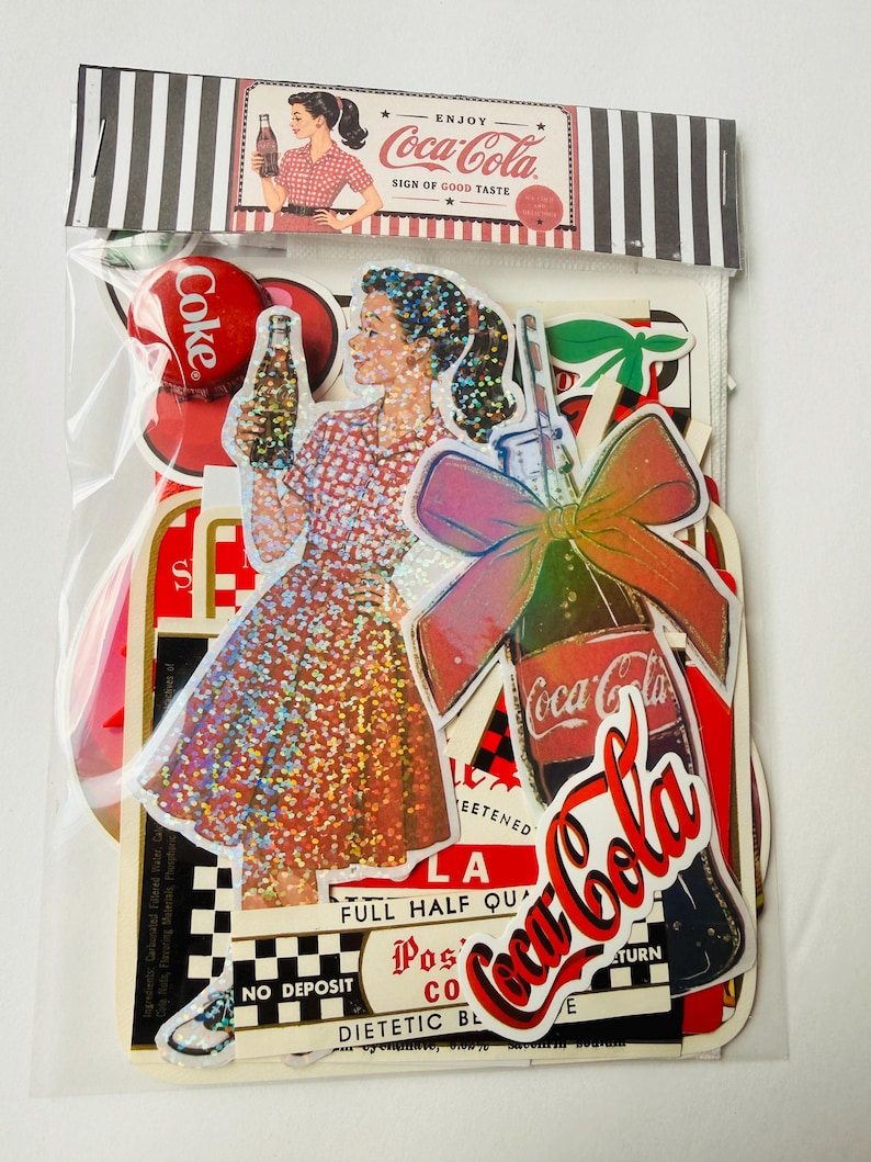 May include: A collection of Coca-Cola themed stickers in a clear plastic bag. The stickers feature a woman in a red checkered dress holding a bottle, a bottle with a large bow, and various vintage-style Coca-Cola logos and text labels.