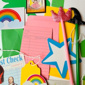 May include: A colourful assortment of craft items, featuring a pink crown wand, a black witch hat wand, a rainbow, and a star. Also included are library cards, tags, and a vintage postcard with the words "Magic Wand".