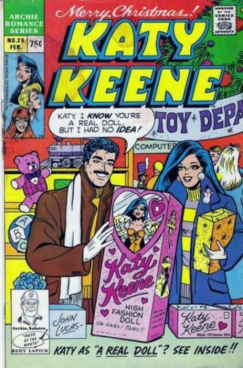 Pu&ograve; includere: Copertina di fumetto a tema natalizio con "Katy Keene". Un uomo e una donna tengono in mano una scatola di bambole "Katy Keene". Il testo recita "Katy as a real doll? See inside!" e "High Fashion Doll".