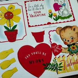 May include: A sheet of vintage Valentine's Day cutouts. Designs include a smiling flower with "Yes," "No," and "Maybe" petals, a bunny holding a heart, and a teddy bear with a heart that says "I love you."