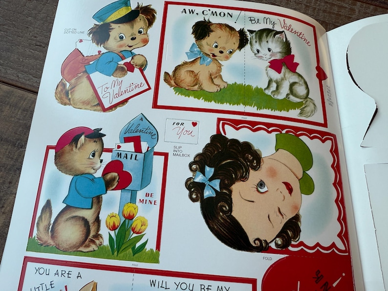 May include: A selection of vintage Valentine's Day cards featuring cartoon animals and a girl. The cards include a dog in a uniform, a puppy and kitten, and a cat with a mailbox. Text includes "To My Valentine" and "Be Mine."