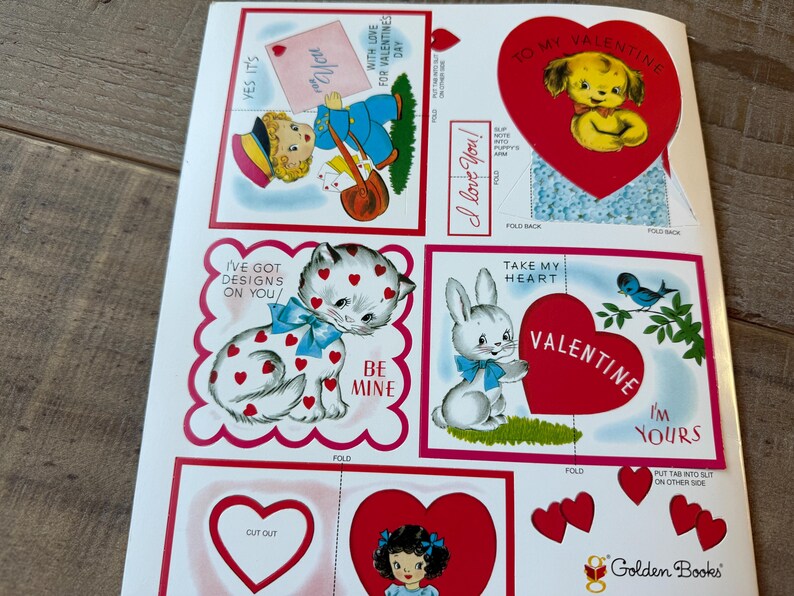May include: A sheet of vintage Valentine's Day cutouts with illustrations of a puppy, a cat, and a bunny. The designs include hearts, bows, and the phrases "I love you" and "Be Mine."