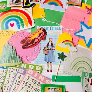 May include: A vibrant collection of Wizard of Oz-themed items, including images of Dorothy, the Wicked Witch's hat, ruby slippers, playing cards, rainbows, bingo cards, and a tea bag. The arrangement creates a nostalgic feel, with a variety of colours and shapes on a white background.