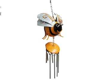May include: A metal wind chime featuring a cartoon bee with yellow and black stripes, white wings, and black eyes. The bee is hanging from a chain and has a round, yellow metal disc with silver chimes hanging below.