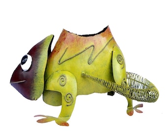May include: A metal chameleon sculpture in shades of green, yellow, and brown. The sculpture features a coiled tail and decorative wire accents. The chameleon has a large eye and is designed to hold a small item.