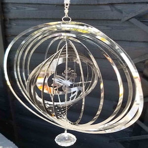 May include: A silver metal wind chime featuring a fairy design and a crystal prism hanging from the bottom.