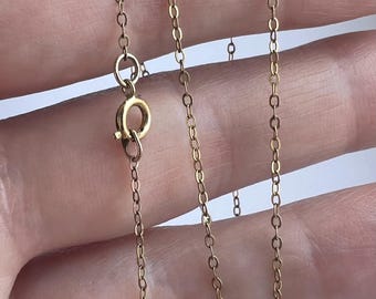 May include: A delicate gold-colored chain necklace with a spring ring clasp. The chain is composed of small, oval-shaped links. The necklace is shown against a neutral background.