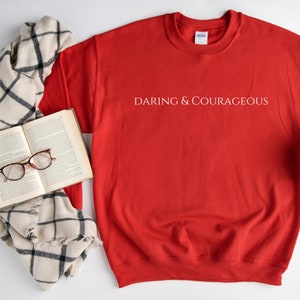 May include: Red sweatshirt with the text "Daring & Courageous" printed in white on the front.