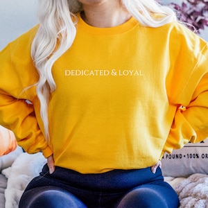 May include: A yellow sweatshirt with the text "DEDICATED & LOYAL" printed in white on the front.