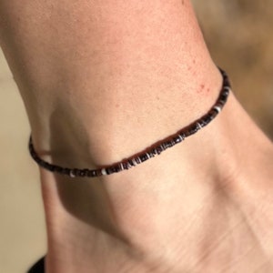 May include: A black and white beaded anklet with small, round beads.