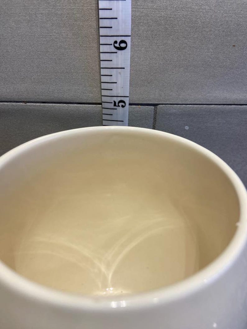 May include: A white ceramic mug with a smooth, glossy finish. The inside of the mug is empty.