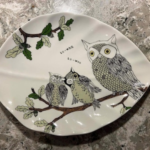 May include: White ceramic leaf-shaped serving dish with an owl family illustration. The design features three owls perched on a branch with green leaves and the text "tu-whit, tu-woo". The owls are in shades of gray, green, and white.
