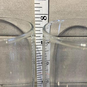以下が含まれることがあります： 2つの透明なグラスの間にメジャーがあります。メジャーはグラスの高さが約17.8cmであることを示しています。グラスはシンプルでクラシックなデザインです。