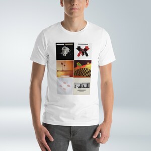 Puede incluir: Camiseta blanca con un collage de seis portadas de &aacute;lbumes. Las portadas presentan una variedad de im&aacute;genes, incluyendo una bombilla, una palmera, un patr&oacute;n de cuadros y una silueta de una persona.