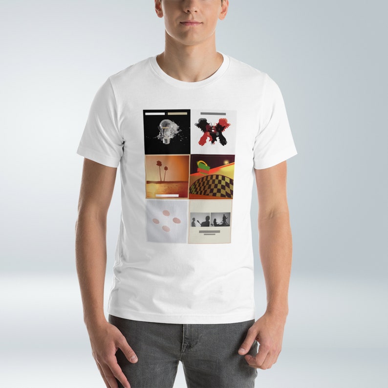Puede incluir: Camiseta blanca con un collage de seis portadas de &aacute;lbumes. Las portadas presentan una variedad de im&aacute;genes, incluyendo una bombilla, una palmera, un patr&oacute;n de cuadros y una silueta de una persona.