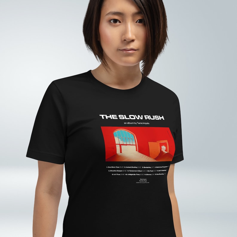 May include: Black t-shirt with a white print of the album cover for "The Slow Rush" by Tame Impala. The album cover features a red room with a window and a door.