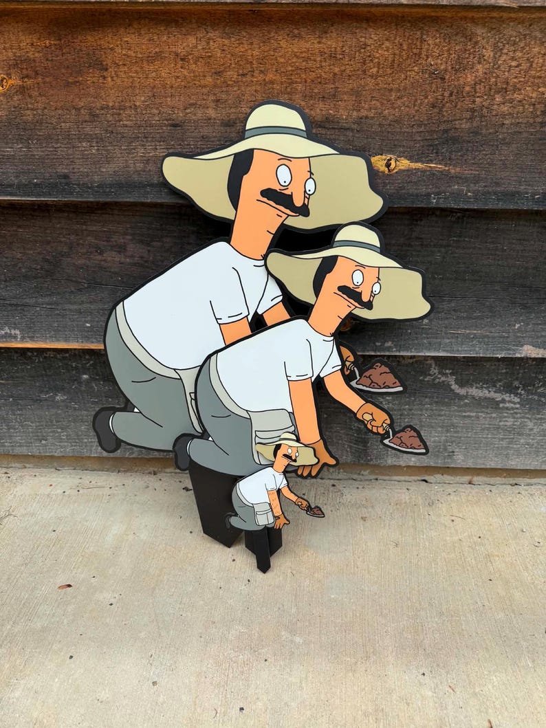 Puede incluir: Un recorte de madera en capas que muestra tres figuras de dibujos animados id&eacute;nticas con bigote, que llevan un sombrero beige de ala ancha, una camiseta blanca y pantalones grises. Cada figura est&aacute; arrodillada y sostiene una peque&ntilde;a paleta.