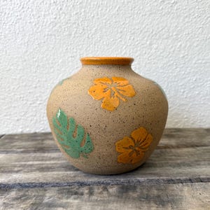 May include: A set of three ceramic mugs with a speckled, matte finish. The mugs are in shades of cream, light gray, and dark gray. Each mug has a simple, minimalist design, perfect for coffee or tea.