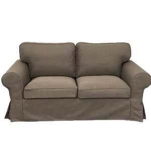 May include: A brown fabric sofa with a tufted back and rolled arms. The sofa has a skirt around the bottom.