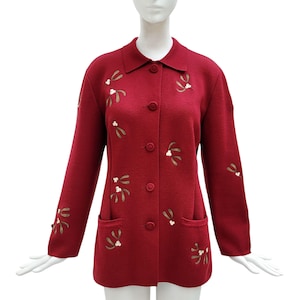 May include: A burgundy button-down jacket with long sleeves and a collared neckline. The jacket features two front pockets and is adorned with embroidered mistletoe designs in shades of green, white, and gold. The jacket is displayed on a mannequin.