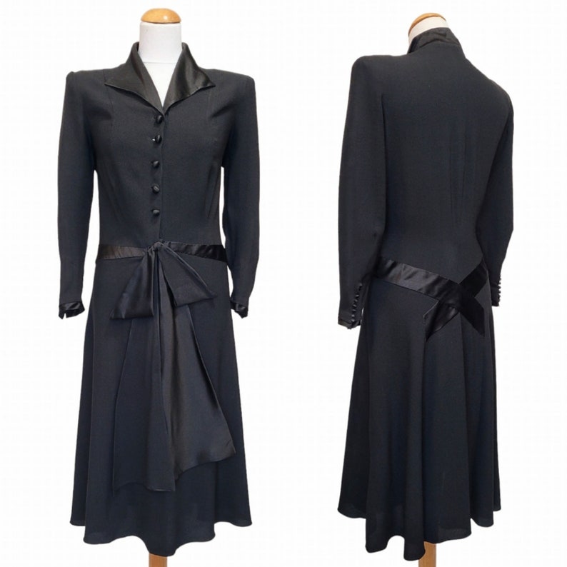 Puede incluir: Un vestido negro con un lazo de sat&eacute;n en la cintura y mangas largas. El vestido tiene un corpi&ntilde;o ajustado y una falda acampanada.