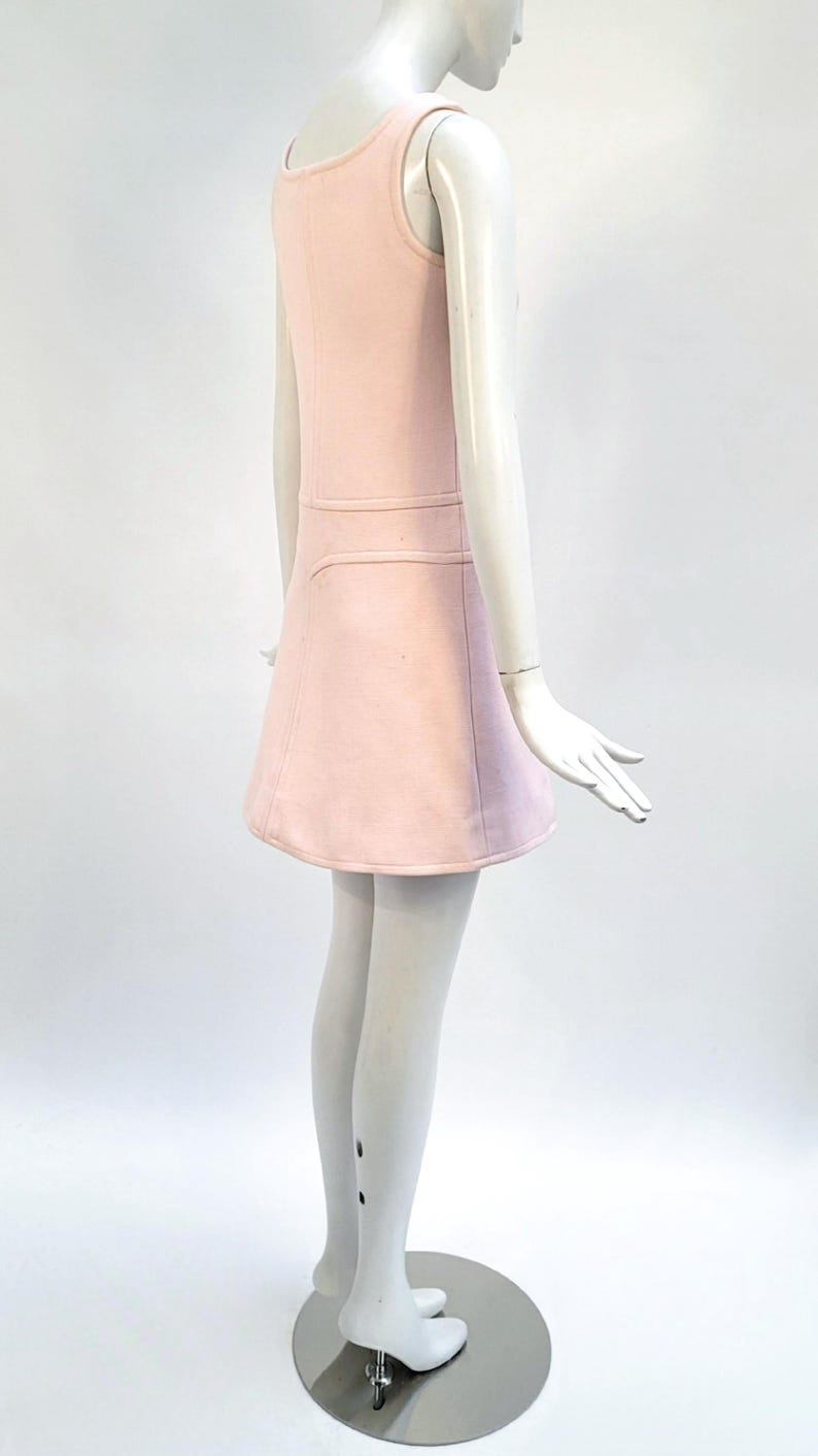 Puede incluir: Vestido rosa claro sin mangas con cuello redondo y falda acampanada. El vestido presenta una costura horizontal en la cintura y se muestra en un maniqu&iacute;. El vestido es de color liso y parece estar hecho de una tela suave.