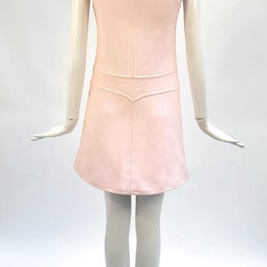 Puede incluir: Vestido rosa claro sin mangas con cuello redondo y falda acampanada. El vestido presenta un corpi&ntilde;o entallado con un sutil detalle de costura y una cintura decorativa. El vestido se exhibe en un maniqu&iacute;.