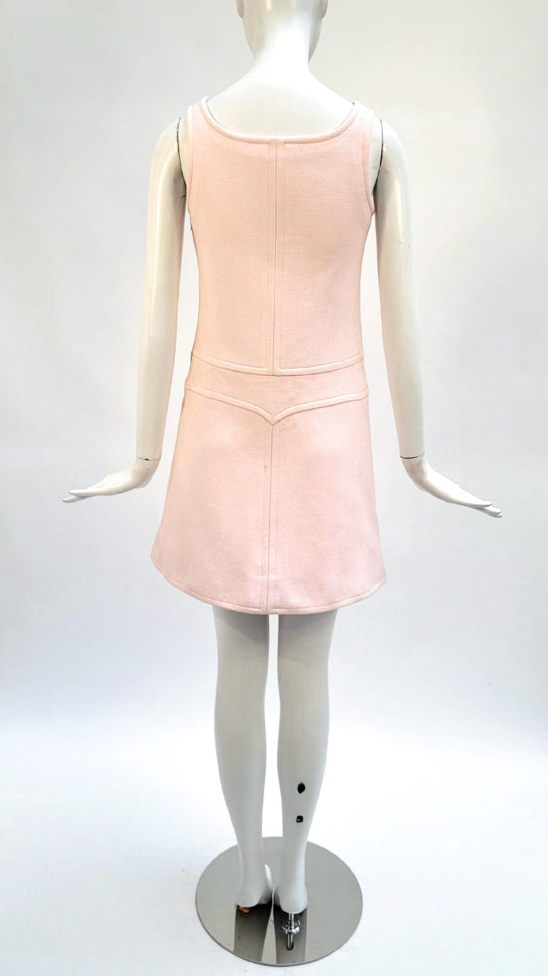 Puede incluir: Vestido rosa claro sin mangas con cuello redondo y falda acampanada. El vestido presenta un corpi&ntilde;o entallado con un sutil detalle de costura y una cintura decorativa. El vestido se exhibe en un maniqu&iacute;.