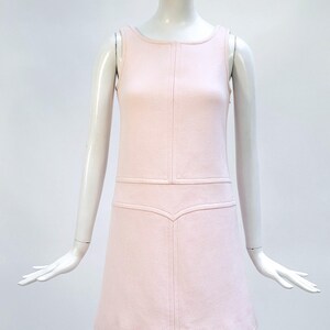 Puede incluir: Vestido rosa claro sin mangas con cuello redondo y corpi&ntilde;o entallado. El vestido presenta una falda en forma de A y costuras decorativas. El vestido se exhibe en un maniqu&iacute;.