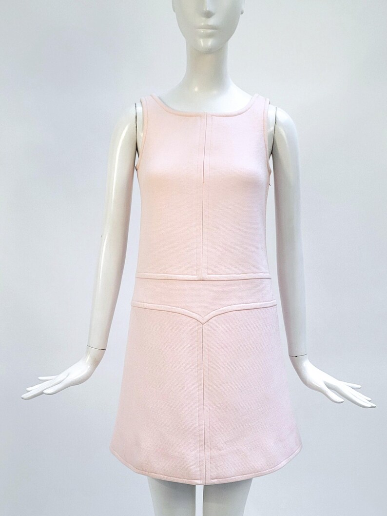 Puede incluir: Vestido rosa claro sin mangas con cuello redondo y corpi&ntilde;o entallado. El vestido presenta una falda en forma de A y costuras decorativas. El vestido se exhibe en un maniqu&iacute;.