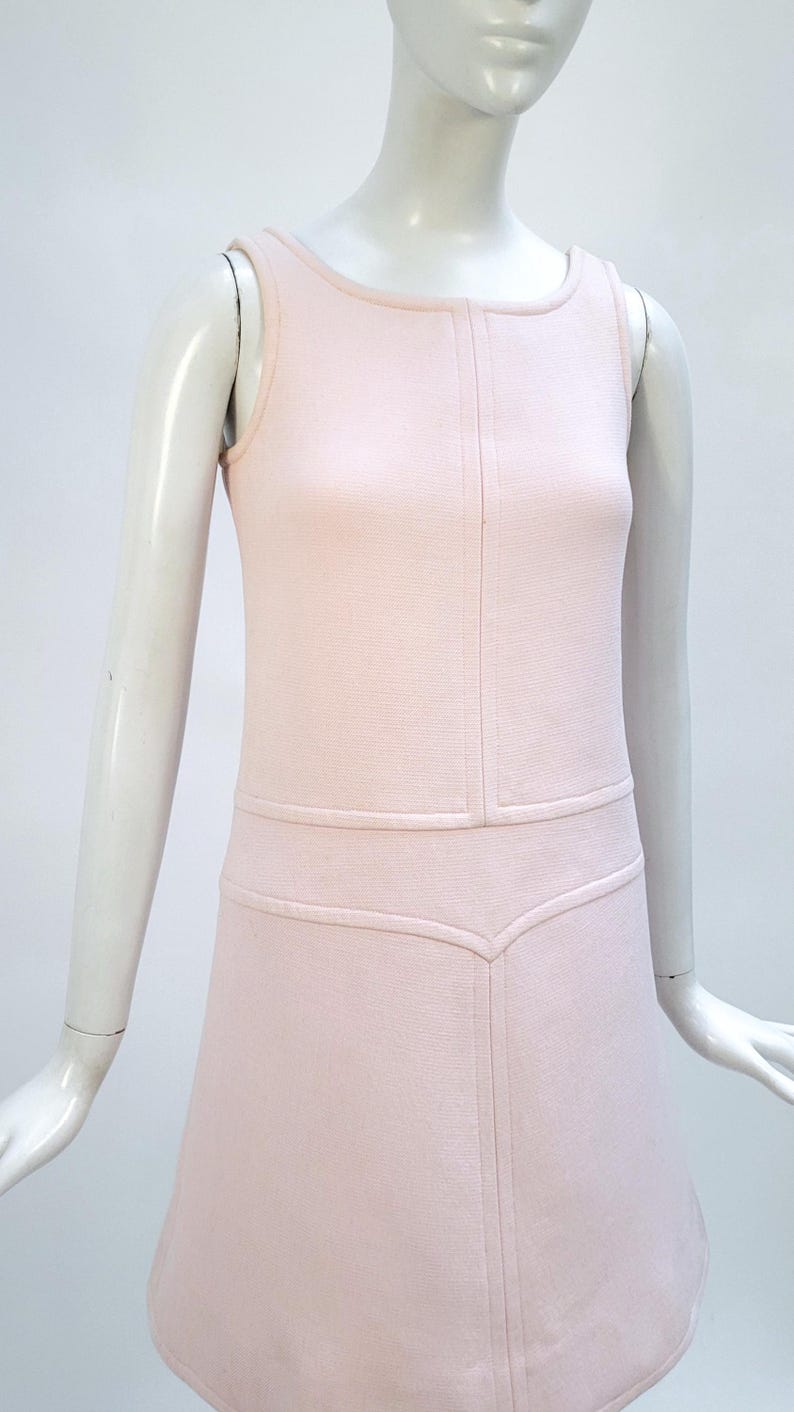 Puede incluir: Vestido rosa p&aacute;lido sin mangas con cuello redondo. El vestido presenta costuras verticales en la parte delantera y una falda sutil en forma de A. El vestido se exhibe en un maniqu&iacute;.