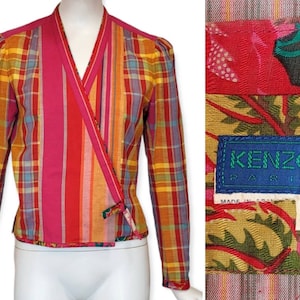 Puede incluir: Una chaqueta de envoltura de cuadros rosa, naranja, amarillo y azul con un forro de estampado floral. La chaqueta tiene cuello en V y mangas largas. La etiqueta dice "KENZO PARIS" y "38".