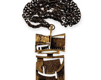 May include: A gold-toned pendant necklace with a geometric design. The pendant is made of multiple pieces of metal that are joined together to create a unique and abstract shape.