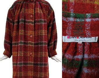 May include: A vintage Saint Laurent coat in a red, orange, green, and yellow plaid pattern. The coat features a high collar, large buttons, and long sleeves. The label reads "Saint Laurent rive gauche 36".