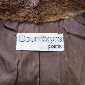 May include: A close-up shot of a brown fur collar and a brown fabric lining. The lining has a label with the text "Courr&egrave;ges paris" in a white rectangle.