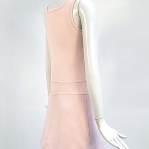 Puede incluir: Un vestido rosa claro sin mangas con cuello redondo y falda acampanada. El vestido presenta un detalle de costura horizontal en la cintura y una sutil textura acanalada. El vestido se exhibe en un maniqu&iacute;.
