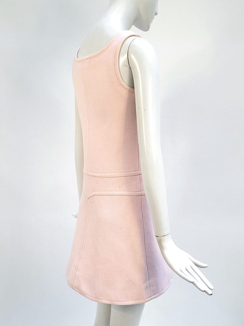 Puede incluir: Un vestido rosa claro sin mangas con cuello redondo y falda acampanada. El vestido presenta un detalle de costura horizontal en la cintura y una sutil textura acanalada. El vestido se exhibe en un maniqu&iacute;.