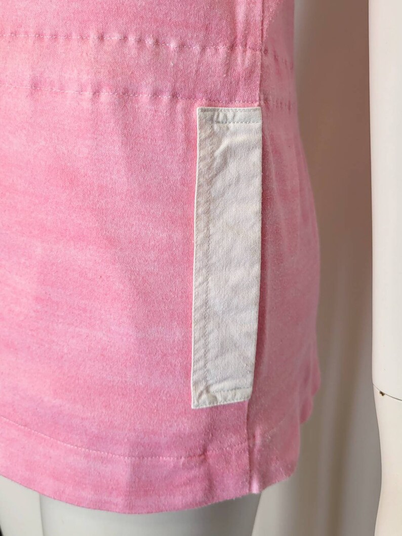 May include: A pink cotton t-shirt with a white patch pocket on the side.