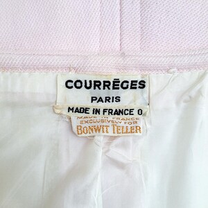 Puede incluir: Primer plano de una tela rosa claro con forro blanco. La etiqueta dice "COURR&Egrave;GES PARIS MADE IN FRANCE EXCLUSIVAMENTE PARA BONWIT TELLER."
