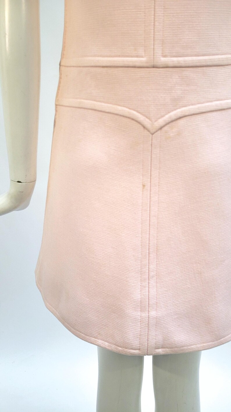 Puede incluir: Vestido rosa claro con corpi&ntilde;o entallado y falda acampanada. El vestido presenta un detalle de costura decorativo en la cintura y un dobladillo curvo. La tela tiene una textura sutil y el vestido parece estar hecho de un material ligero.