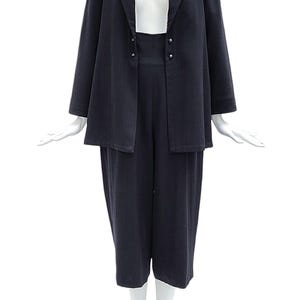 May include: A dark navy blue two-piece set consisting of a long-sleeved blazer with a notched lapel and two small silver-toned buttons at the waist, paired with matching high-waisted cropped trousers that fall below the knee in a straight cut.