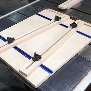 May include: A wooden jig with four adjustable clamps and blue tracks for woodworking projects.