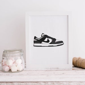 May include: A white framed print of a black and white Nike sneaker with a white swoosh logo.